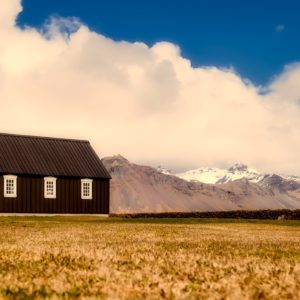 Small brown church against mountains in field